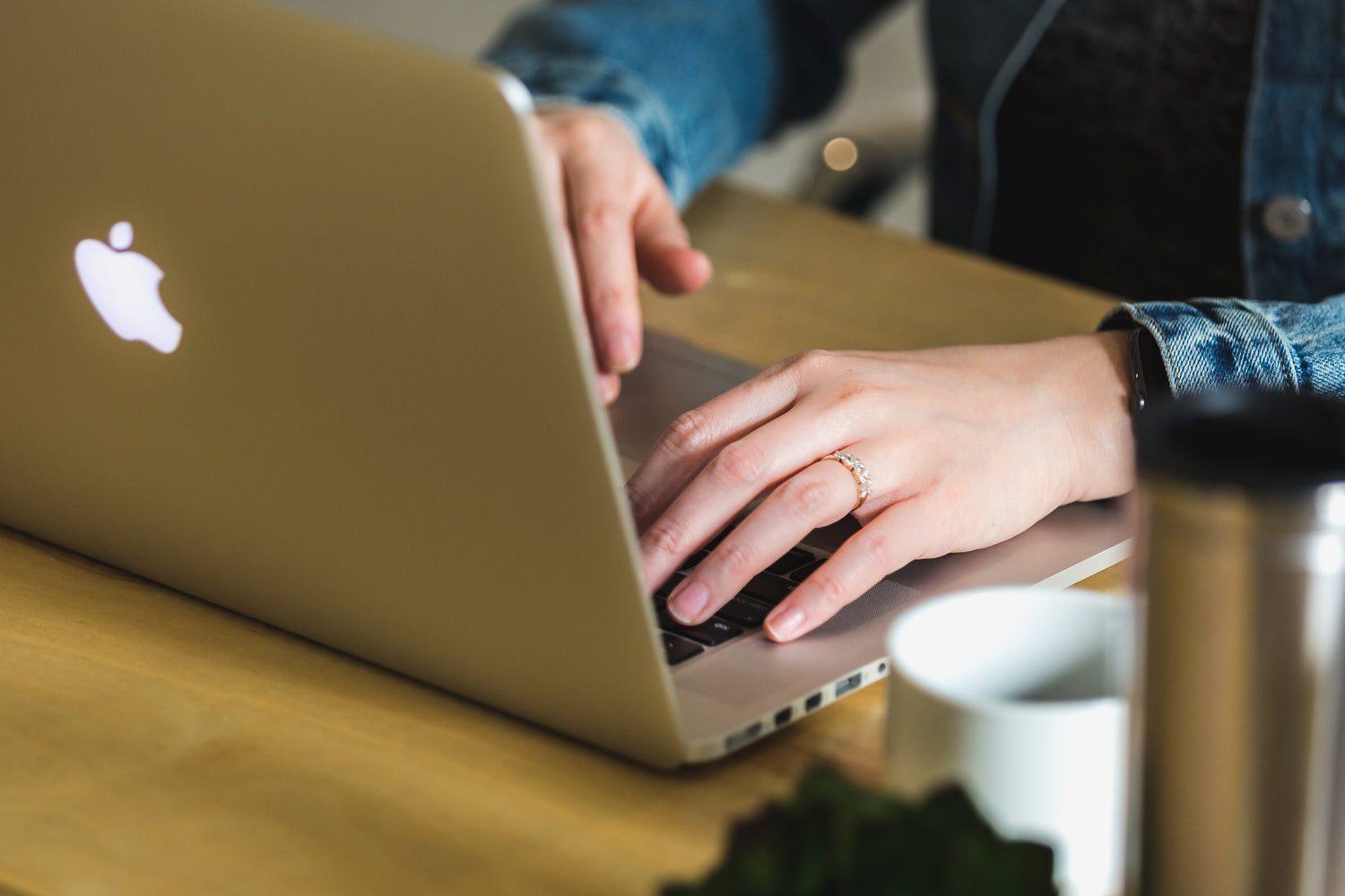 "Woman typing on an Apple computer at a desk with a coffee cup, representing an initial consultation for vacation rental management.
