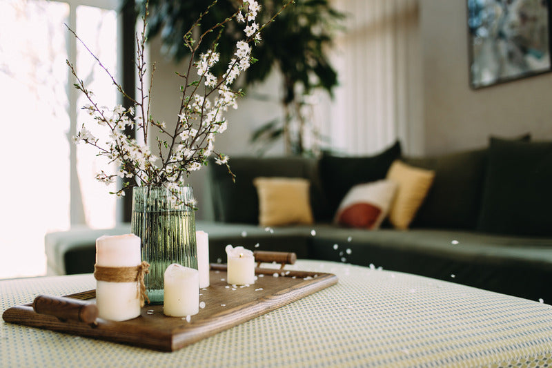 Living room interior with a green sofa in the background and a close-up of a coffee table ottoman, warmly lit to create an inviting atmosphere.